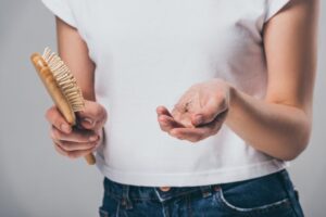 woman holding hairbrush and fallen hair